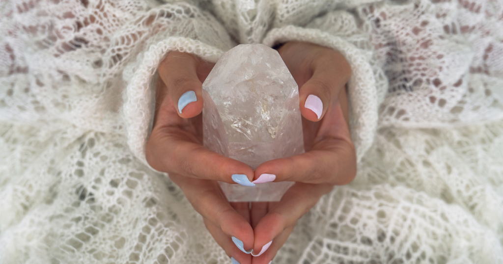 Woman sitting holding a natural crystal.
